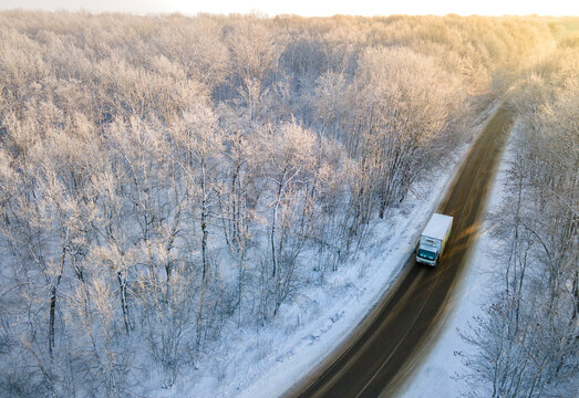 White Lorry truck on the road surrounded by winter forest. Aerial top view