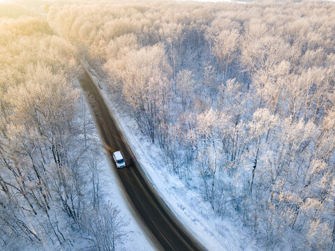 Car on the road surrounded by winter forest. Aerial top view