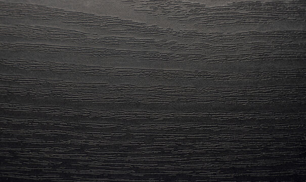 Photo of an ebony texture. The wooden background is black.