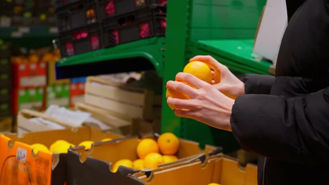 Woman choice an orange in her hand in a supermarket. Citrus fruits are a source of vitamin C with beriberi