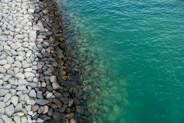 Aerial view to the shore with white stones and beautiful sea, with no waves or people. Amazing coastline. 