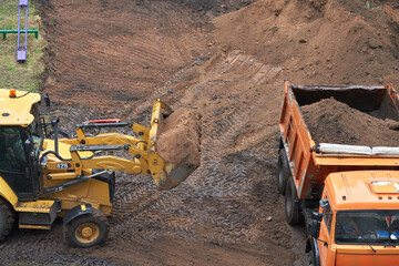 Earthworks in cramped urban conditions. The minitractor ladles the soil into the truck body.