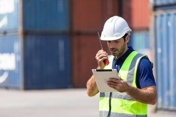 foreman manager working through a radio communication with the workers in the container yard at port of import and export goods.