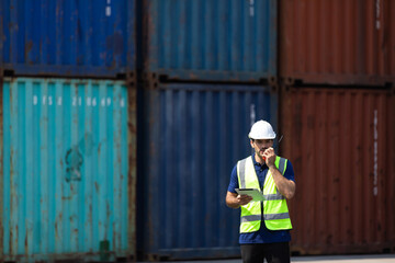foreman manager working through a radio communication with the workers in the container yard at port of import and export goods.