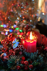 Christmas composition with festive decor, glass ball with angel and candle, blurred shiny glittering dark background. Christmas holiday scene. winter season. garland lights bokeh