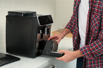Man fixing coffee machine at table indoors, closeup