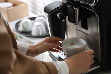 Woman preparing fresh aromatic coffee with modern machine in office, closeup