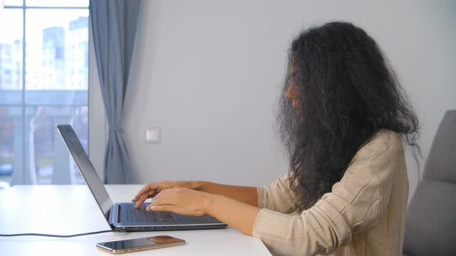 Freelance writer woman typing text on laptop keyboard. Professional free lancer female working from home online during lockdown. BIPOC lady doing distant work and using modern internet technology