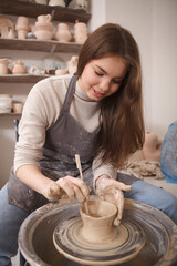Fototapeta na wymiar Vertical portrait of a lovely female artist making pottery on potters wheel