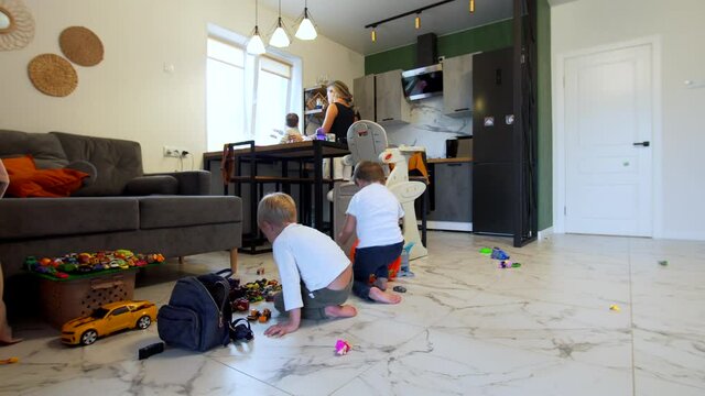 Timelapse: Korean family: parents with one year old son in the kitchen, the 4 years old son is playing small cars on the floor with his friend. Domestic environment. Light room