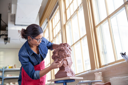 Artist Working On Clay Sculpture In Art Studio