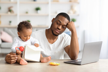 Parental Burnout. Black man tired of working and taking care of baby