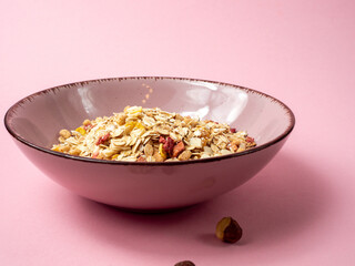 Muesli in a pink cup on a pink table. Muesli on a pink background.