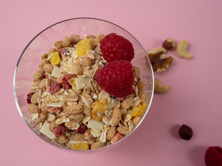 Muesli in a glass glass and berries on a pink table. Muesli on a pink background.