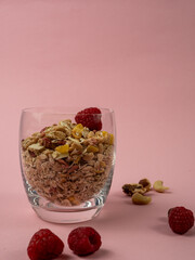 Muesli in a glass glass and berries on a pink table. Muesli on a pink background.