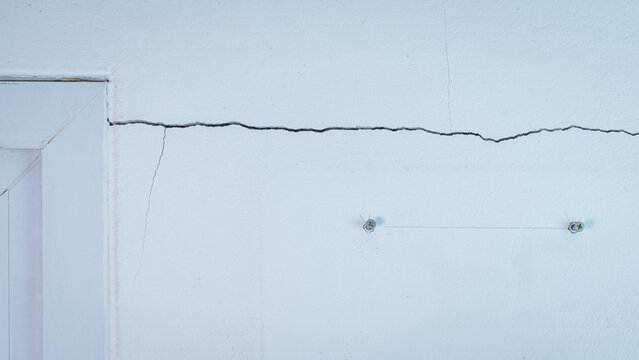 Cracks on the wall. The crack in the cement wall at the window sill, caused by the subsidence of the ground, causing a slit at an oblique angle.