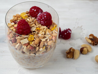 Muesli in a glass glass and berries on a white table. Muesli on a wooden white background.