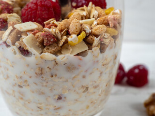Muesli in a glass glass and berries on a white table. Muesli on a wooden white background.