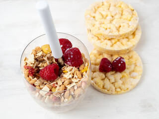 Muesli in a glass glass and berries on a white table. Muesli on a wooden white background.