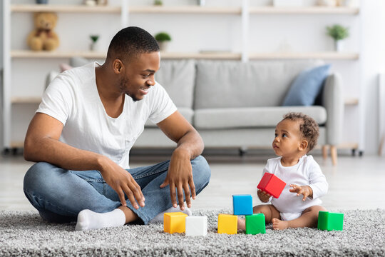 Black Father And His Infant Baby Playing With Building Blocks At Home