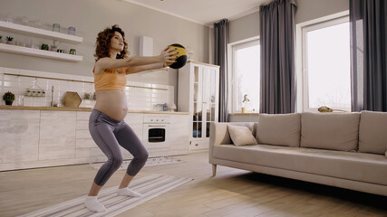 Fototapeta na wymiar Pregnant woman training with slam ball at home
