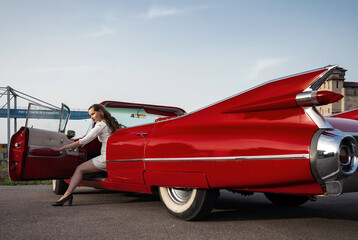 60-s oldtimer red Cadillac and a beautiful young girl - obrazy, fototapety, plakaty