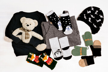 Knitted romper, sweater, jumper, socks, hat, bodysuit, mittens, teddy bear. Set of Fashion newborn baby childs clothes and accessories in pastel colors on white background. Flat lay, top view