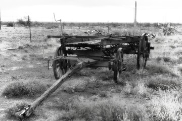 Fototapeta na wymiar Black and white image of an abandoned wooden wagon or cart in an arid field