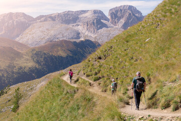 Three hikers of different age and gender in the beautiful mountains of Dolomites Italian Alps. Passo Sella - Sassolungo, South Tyrol, Italy