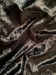 black crushed velvet background, velvet catching light on folds and wrinkles of black drape 