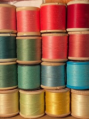 spools of cotton thread background from red, pink blue to green background pattern with copy space 
