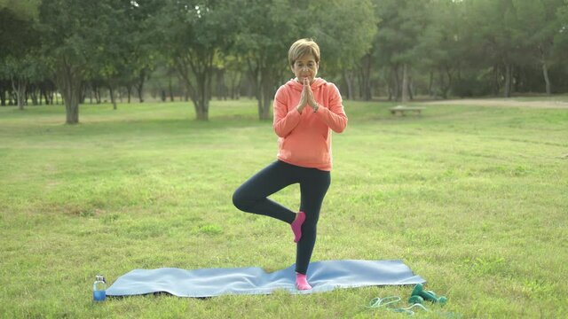 Senior woman doing yoga meditation routine outdoor at city park