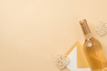 Top view photo of bottle of white wine decorative rattan hearts and envelope with paper sheet on isolated beige background with blank space