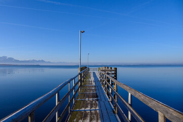 Calm Chiemsee in winter with ducks mountains and clear sky fog