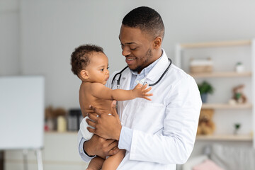 Portrait Of Young Black Pediatrician Holding Adorable Little Infant Boy In Hands