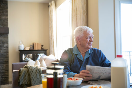 Senior man reading newspaper at breakfast table
