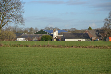 farmhouse with silo and barns on a sunny day in winter