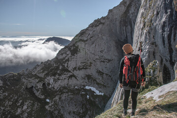 chica en la montaña con una mochila y mar de nubes de fondo