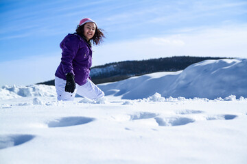 Fototapeta na wymiar Young woman walking in snow in snowy cold winter landscape.