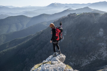 chica en la monta&ntilde;a con una mochila y mar de nubes de fondo