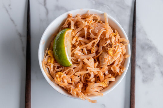 A close up of a pad Thai bowl on a counter.