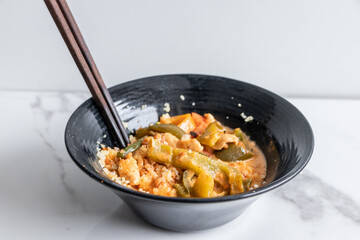 Close up of a red curry bowl on a white brackground.