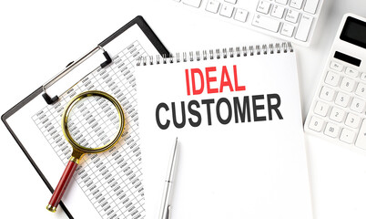 Office desk table with keyboard, notepad ,chart and calculator. Top view with text IDEAL CUSTOMER