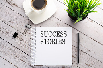 Cofee cup, notepad,pen on the wooden background. Business concept. Text SUCCESS STORIES