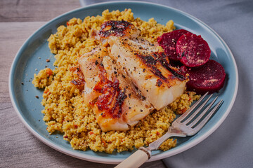 Blackened cod fillet on a bed of spicy couscous,garnished with beetroot.