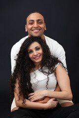 Family portrait of a young couple in white T-shirts on a black background. Studio photo .