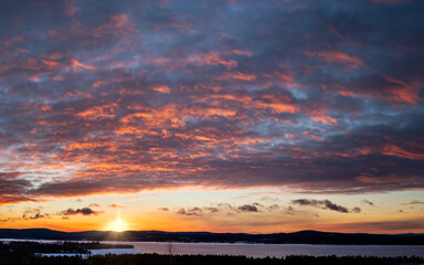 Dramatic sky and sunset over lake Siljan in Dalarna, central region in Sweden, and the winter landscape with the mountains in the background. Photo taken in the small village of Tällberg, Sweden. 