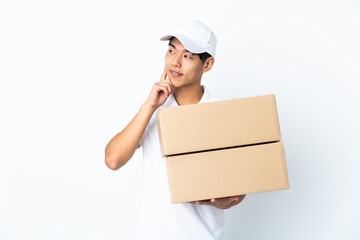 Delivery Chinese man isolated on white background thinking an idea while looking up