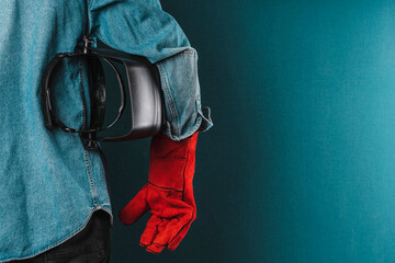 an iron worker wearing red protective gloves and a welder's protective mask. factory worker. labor...