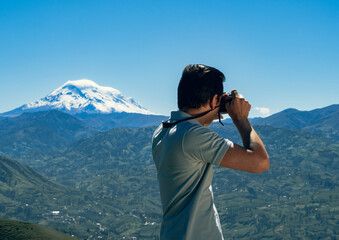 young man on vacation in the andes of ecuador taking a picture of a landscape of the chimborazo volcano